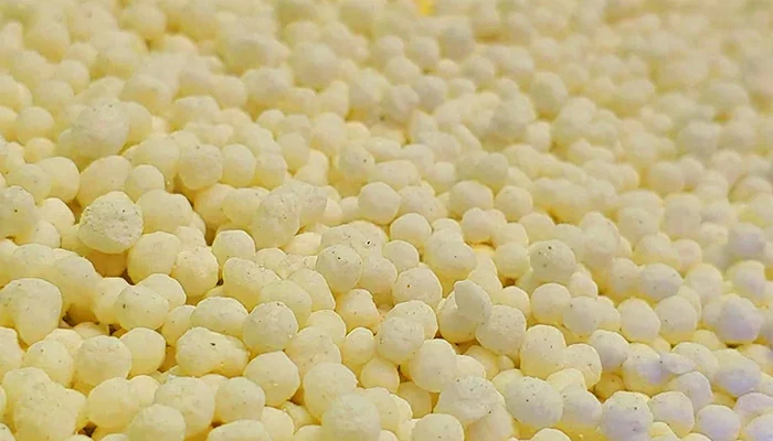 Close-up of pale yellow coated urea granules
